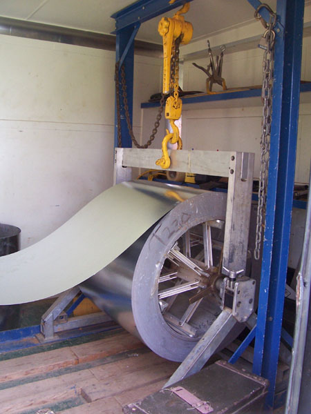 Massive coil of terne metal spooling into the roll former.
