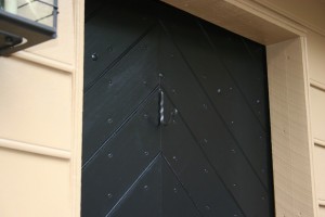 Clench-nailed door, painted.  Hand-wrought hook stands ready to receive traditional seasonal decroations.