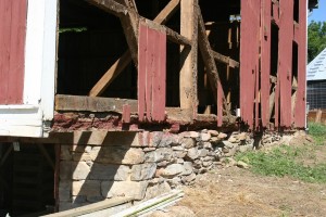 Siding removed shows sill timbers in advanced state of decay.