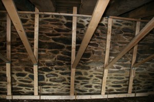 Freshly repointed parlor wall is braced to prevent movement under the pressure from concrete being poured outside.