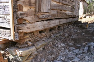 With the foundation stone temporarily removed, the log floor joists are visible.